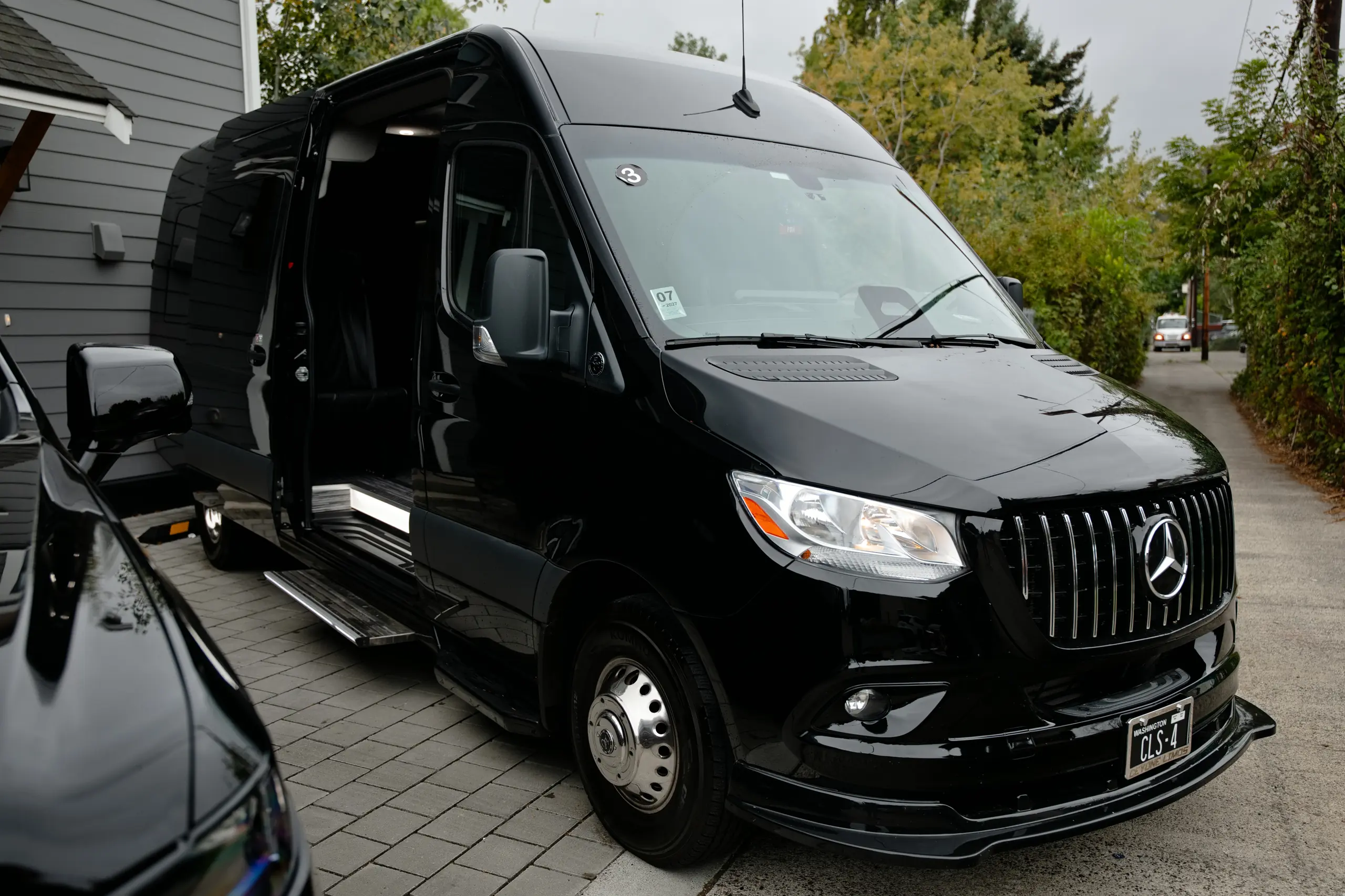 Black Mercedes-Benz Executive Sprinter van with the sliding door open, front three-quarter view